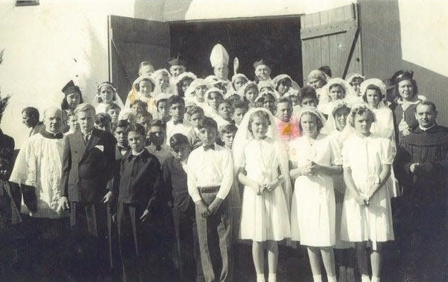 A 1940 photo shows a group confirmation students with church leaders outside of  St. Joan of Arc Church in Victorville.