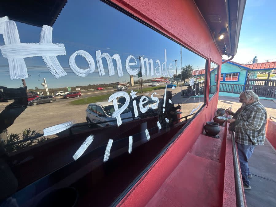 Gary Locklier paints the windows in front of Cafe 290 in Manor. (KXAN: Frank Martinez)