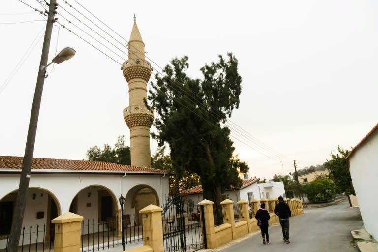 A couple walks past a mosque in the mixed village of Pyla, which lies in the UN-patrolled buffer zone that slices across the island of Cyprus