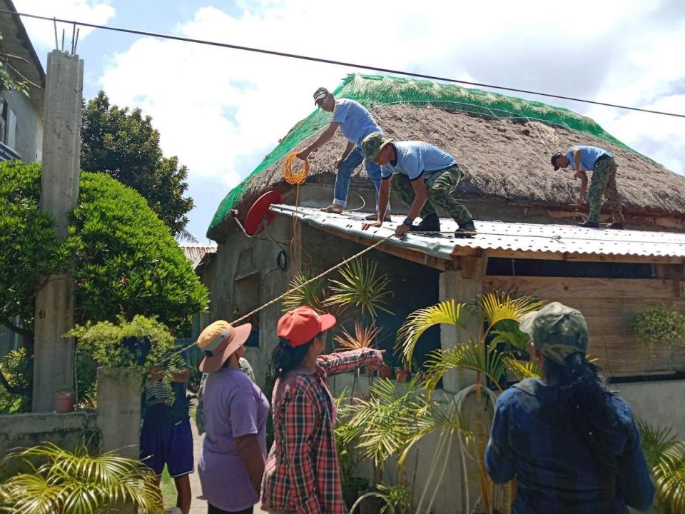 Police personnel helping residents reinforce the roof of their homes in Ivana town, Batanes province, on the very tip of the Philippines, ahead of super Typhoon Mawar grazing the province (AFP/Getty)