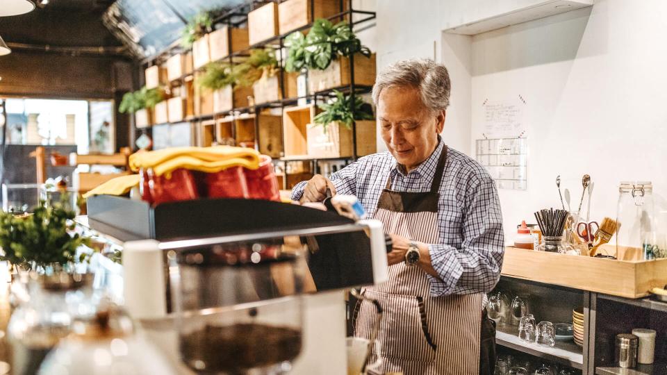 Professional senior barista working in a cafe, preparing coffee.