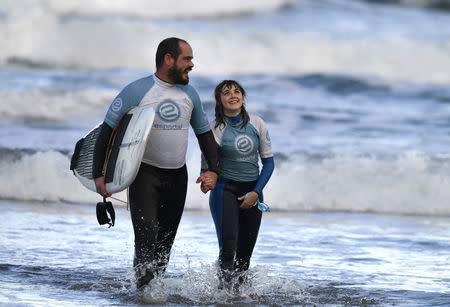 Carmen Lopez Garcia, Spain's first blind female surfer who is to participate in the ISA World Adaptive Surfing Championship, walks with her coach Lucas Garcia after training at Salinas beach, Spain, December 5, 2018. REUTERS/Eloy Alonso