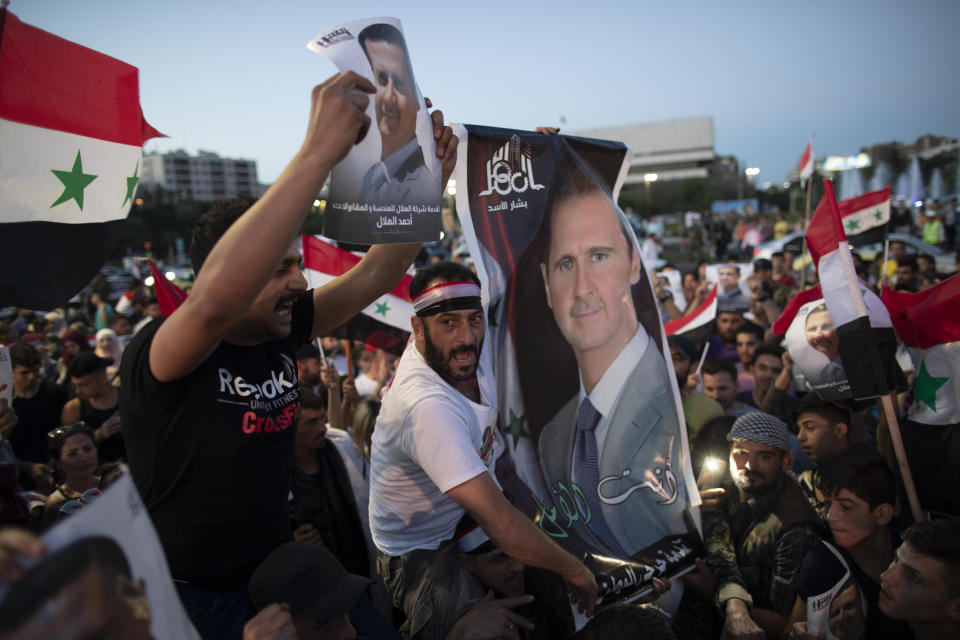 Injured Syrian soldiers supporters of President Bashar Assad hold up national flags and pictures of Assad as they celebrate at Omayyad Square, in Damascus, Syria, Thursday, May 27, 2021. (AP Photo/Hassan Ammar)