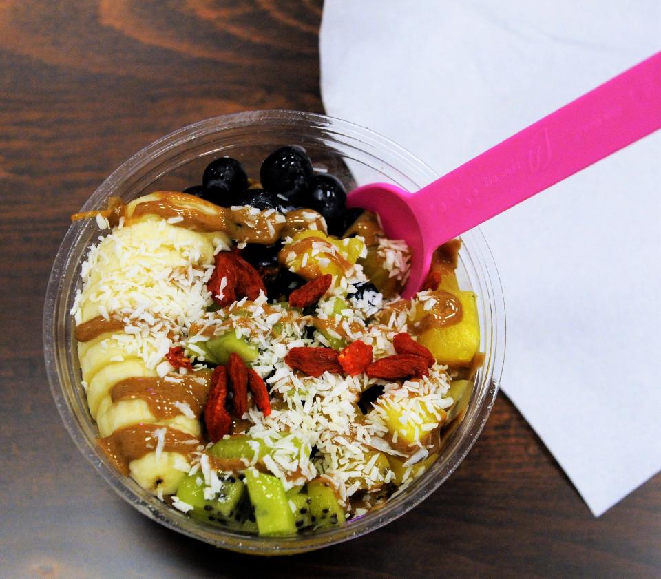 A bowl with frozen coconut and mango fruit purees with granola, fruit, dried goji berries and almond butter toppings at Bowlify Superfoods on Tuesday, Dec. 6, 2022.