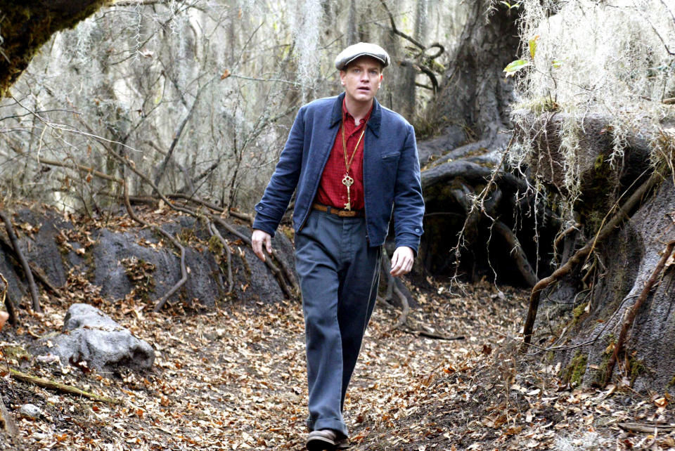 Ewan McGregor walking in the woods with a key around his neck