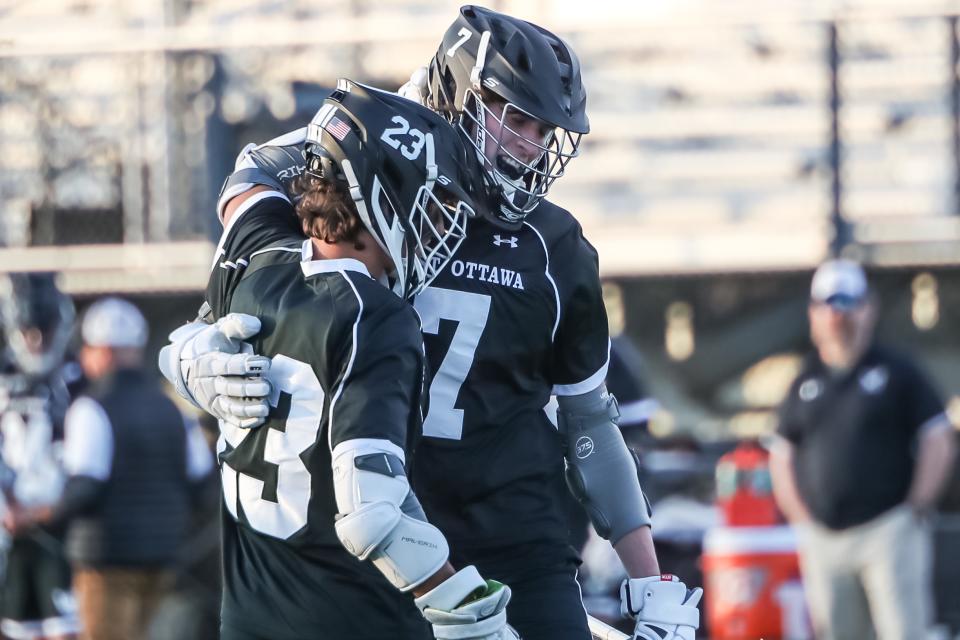 Trent Mulder (right) and Cole Tulgestke (left) embrace after a goal in a West Ottawa lacrosse game
