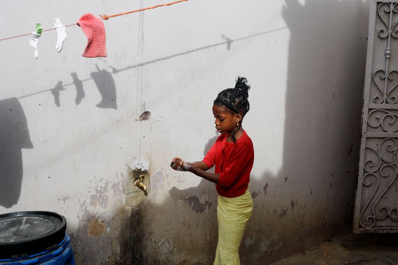 A girl washes her hands at the entrance of her parents house in Pikine, on the outskirts of Dakar