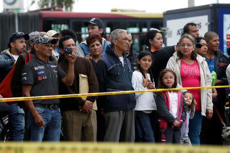 People stand beside a security tape set up close to the scene where a car bomb exploded, according to authorities, in Bogota, Colombia January 17, 2019. REUTERS/Luisa Gonzalez