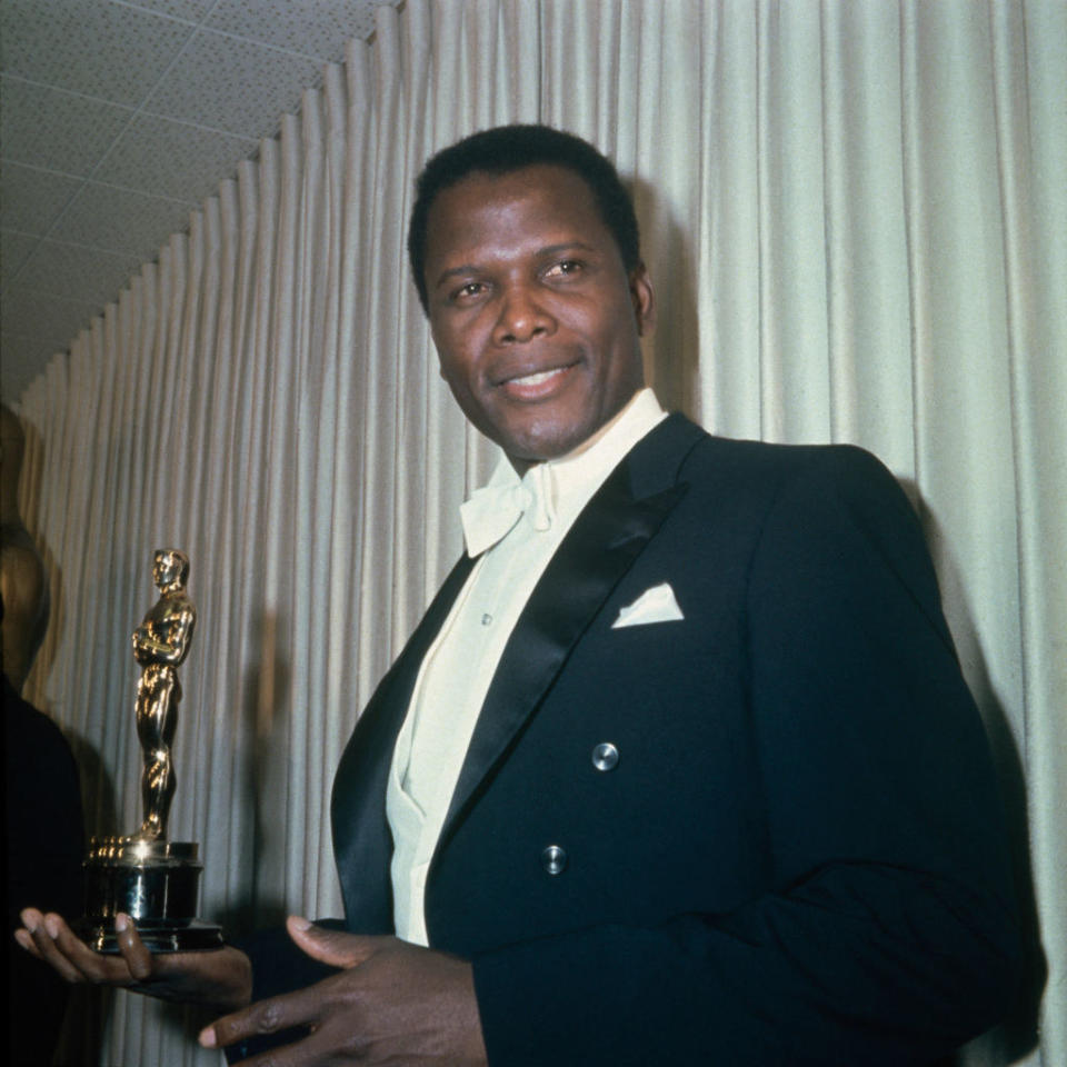 Poitier posing with a golden statue as a presenter