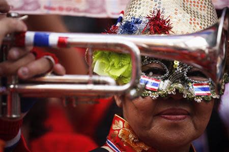 An anti-government protester wears a mask as another plays a trumpet during their march through Chinatown in Bangkok February 1, 2014. REUTERS/Damir Sagolj