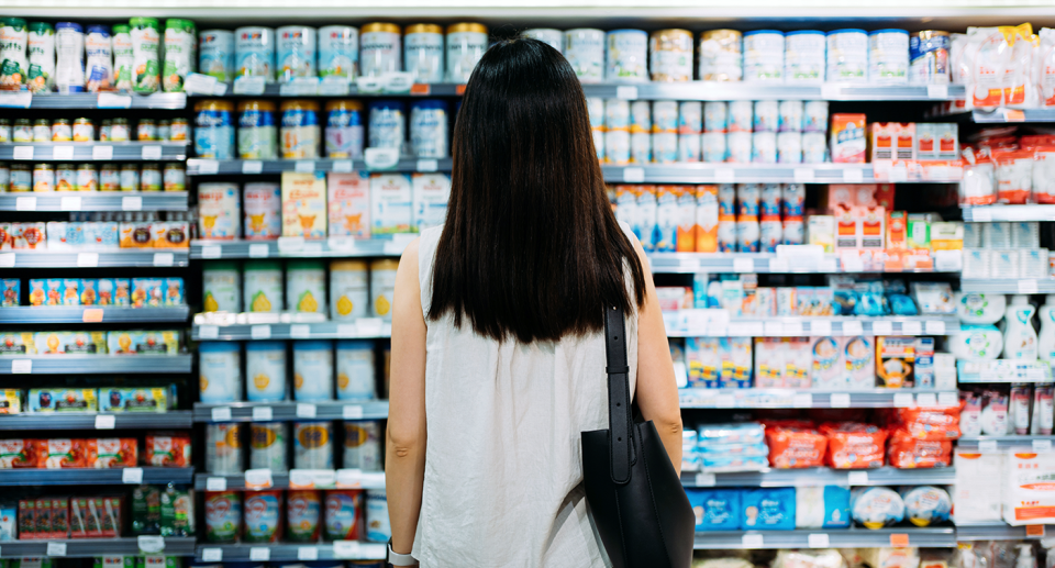 A woman looking inside a supermarket fridge.