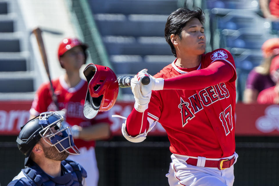 Los Angeles Angels designated hitter Shohei Ohtani, right, knocks off his helmet while fouling off a pitch next to Seattle Mariners catcher Curt Casali, left, during the fourth inning of a baseball game in Anaheim, Calif., Monday, Sept. 19, 2022. (AP Photo/Alex Gallardo)