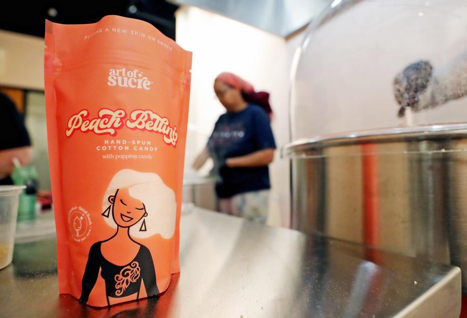 Workers pack bags of Peach Bellini cotton candy at Art of Sucre Monday, Feb. 27, 2023, in Fairlawn, Ohio.