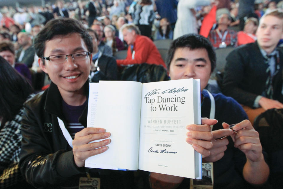 Wei Huang from Shenzhen, China, left, displays a book autographed by Warren Buffett as he waits with other shareholders for the Berkshire Hathaway shareholders meeting to begin, in Omaha, Neb., Saturday, May 4, 2013. Tens of thousands attend Berkshire Hathaway shareholder meeting to hear Warren Buffett and Charlie Munger answer questions for more than six hours. No other annual meeting can rival Berkshire's, which is known for its size, the straight talk Buffett and Munger offer and the sales records shareholders set while buying Berkshire products. (AP Photo/Nati Harnik)