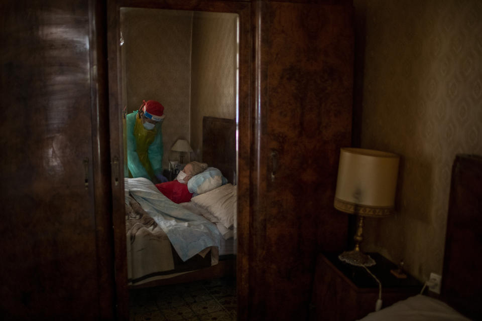 Josefa Ribas, 86, who is bedridden and suffers from dementia, is attended to by nurse Laura Valdes during a home care visit in Barcelona, Spain, April 7, 2020. Ribas' husband, Jose Marcos, fears what will happen if the virus enters their home and infects them. "I survived the post-war period (of mass hunger). I hope I survive this pandemic," he said. (AP Photo/Emilio Morenatti)