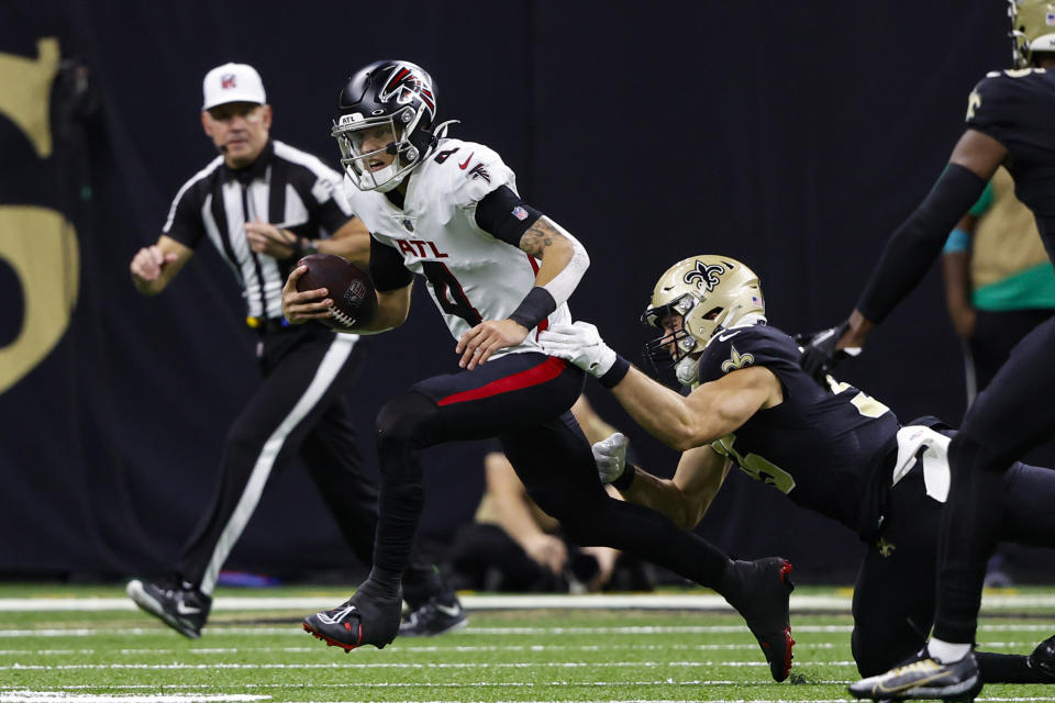 Atlanta Falcons quarterback Desmond Ridder (4) escapes from New Orleans Saints linebacker Kaden Elliss (55) in the first half of an NFL football game in New Orleans, Sunday, Dec. 18, 2022. (AP Photo/Butch Dill)