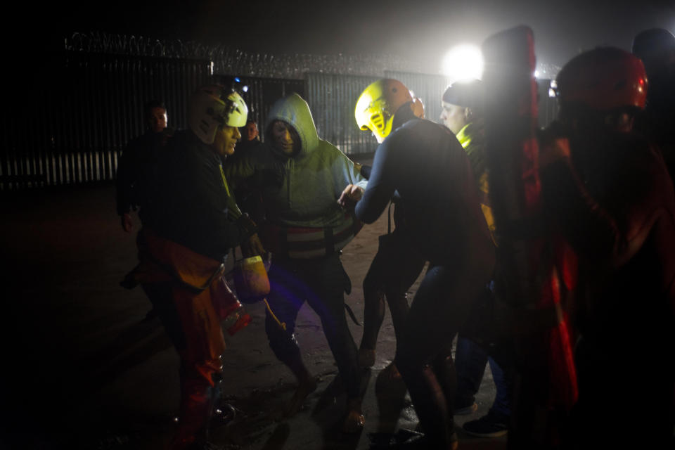 Rescuers hold a Honduran migrant who tried to cross the U.S. border by the sea in Tijuana beach, Mexico, Thursday, Nov. 29, 2018. Aid workers and humanitarian organizations expressed concerns Thursday about the unsanitary conditions at the sports complex in Tijuana where more than 6,000 Central American migrants are packed into a space adequate for half that many people and where lice infestations and respiratory infections are rampant. (AP Photo/Ramon Espinosa)