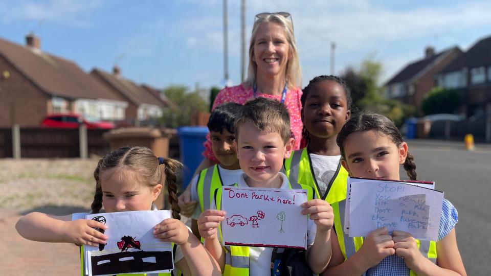 Pupils in high-vis with their head teacher standing in the street