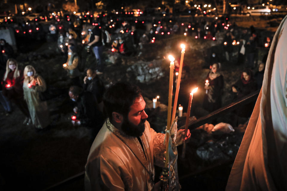 Priests distribute holy light to orthodox worshipers, a few wearing masks for protection against the COVID-19 virus, during a religious service in the Black Sea port of Constanta, Romania, Wednesday, May 27, 2020. (AP Photo/Vadim Ghirda)