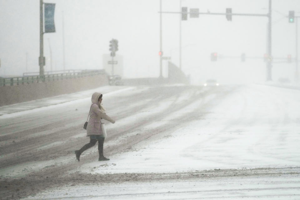 Una mujer cruza una calle en medio de una tormenta invernal, el jueves 22 de diciembre de 2022, en Rosemont, Illinois. (AP Foto/Nam Y. Huh)