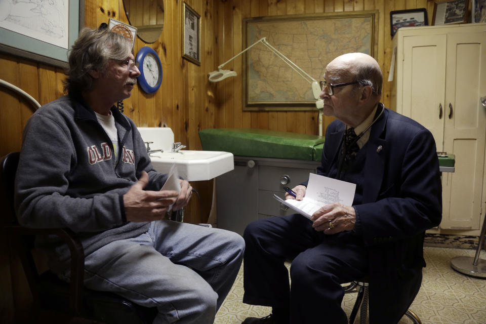 In this Tuesday, Oct. 30, 2012 photo,m Dr. Russell Dohner, right, talks with patient Joe Logsdon about his high cholesterol in Rushville, Ill. Patients line up early outside his office just off the town square, waiting quietly for the doctor to arrive, as he has done for nearly 60 years. (AP Photo/Jeff Roberson)