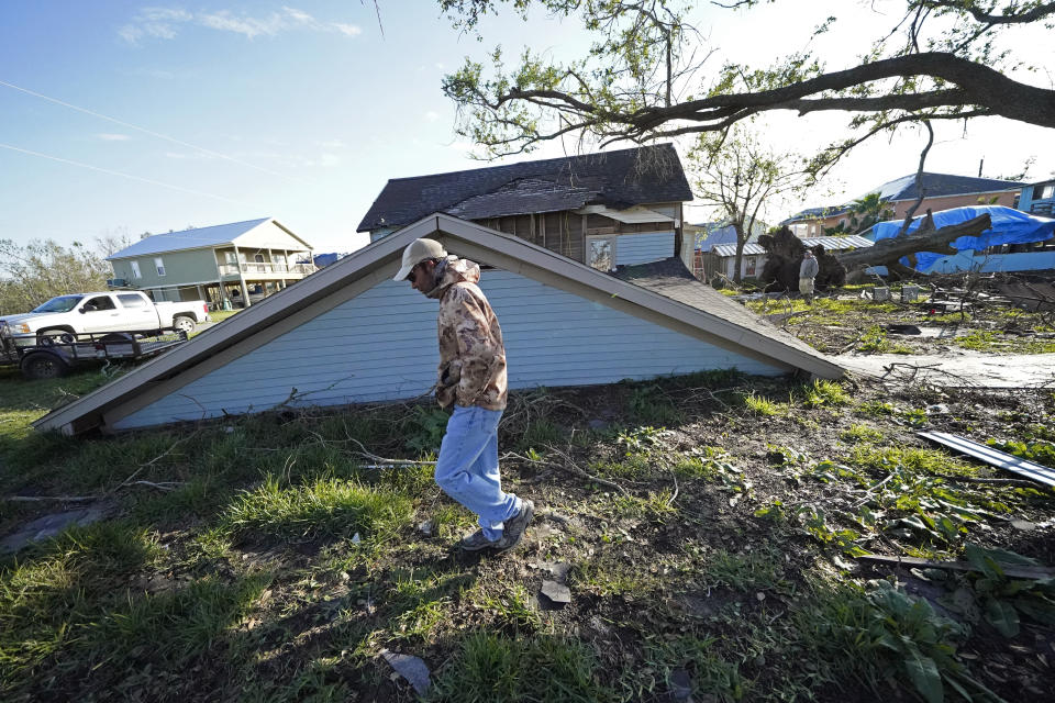 Jack Corbella walks past his neighbor's destroyed home as he assists his other neighbor who just bought the property, after the original owner decided not to rebuild, in the aftermath of Hurricane Laura and Hurricane Delta, in Grand Lake, La., Friday, Dec. 4, 2020. (AP Photo/Gerald Herbert)
