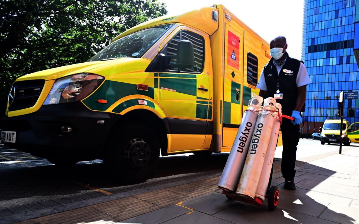 A hospital worker moves oxygen tanks outside the Royal London hospital, as Covid-19 cases continue to rise, on 23 July 2021 - Andy Rain/Shutterstock