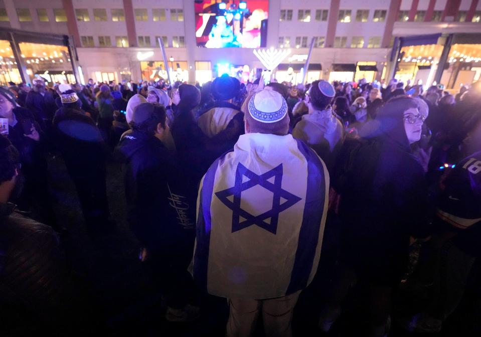 A person wears a flag of Israel during a Chanukah Festival and Gelt Drop, to kick off the first day of Chanukah on Thursday, Dec. 7, 2023. In Georgia, a middle school teacher is facing criminal charges after he allegedly threatened to behead a 13-year-old Muslim student who claimed an Israeli flag hanging in his classroom offended her on Dec. 8, 2023.