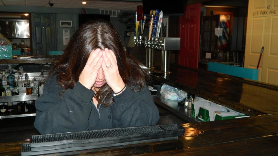 In this March 31, 2014 photo, Gigi Liaguno-Dorr buries her face in her hands as she becomes overwhelmed with emotion while discussing the decision she made to close Jakeabob's, the Union Beach N.J. restaurant she used to operate until having to close it the previous weekend. The original Jakeabob's was destroyed in Superstorm Sandy, and she moved the business a few blocks inland for 2013. But a continuing inability to get timely rebuilding aid forced her to close the restaurant for good on March 28. The reopening of Jakeabob 's was seen as an inspiration to the still-struggling Raritan Bay community. (AP Photo/Wayne Parry)