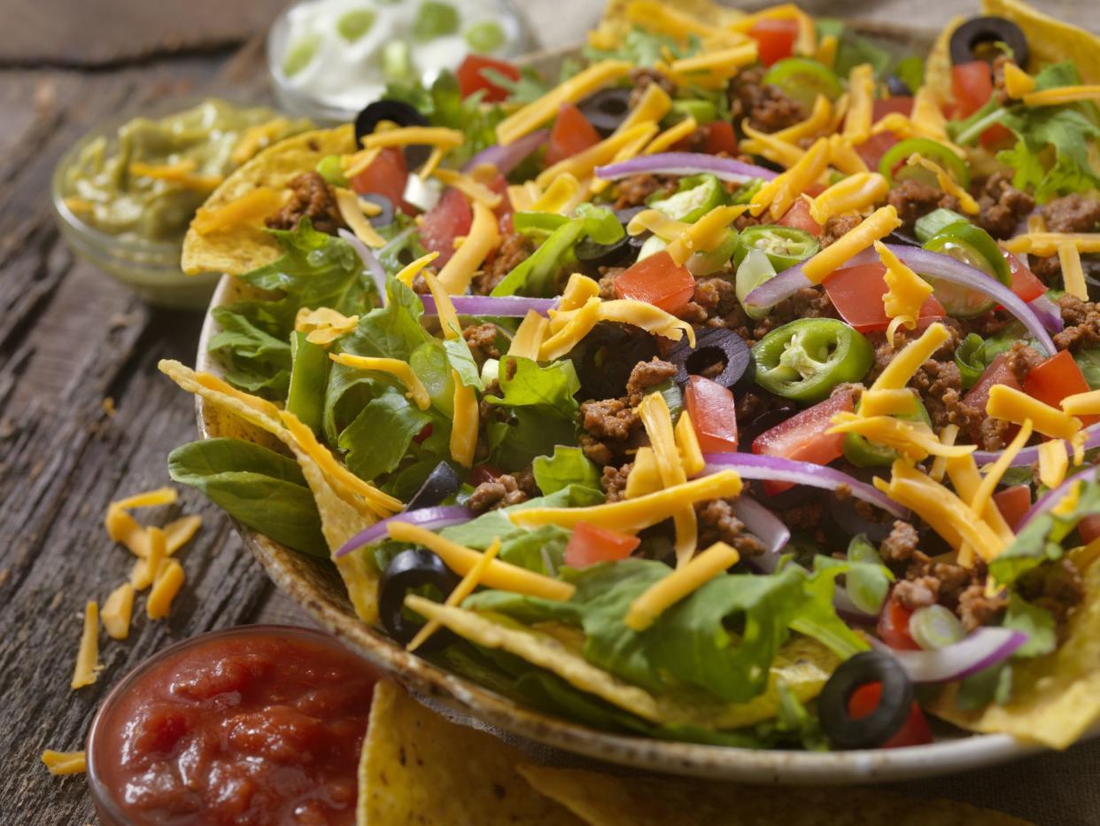 Taco Salad with Spicy Ground Beef, Lettuce, Jalapenos, Black Olives, Green Onions, Tomatoes, Cheddar Cheese, Sour Cream Guacamole and Salsa