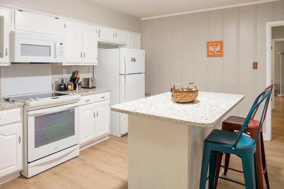 The previously remodeled all-white kitchen features an island that provides additional storage and seating.
