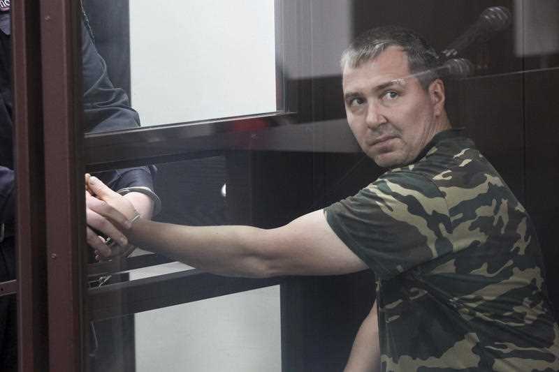 Alexander Popov. who was arrested on suspicion of murder. sits behind the glass in a courtroom in the city of Gorodets.