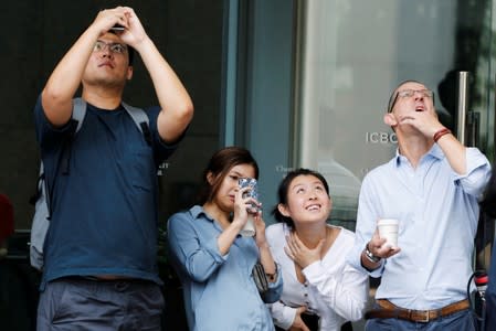 People watch and take photos of French urban climber Alain Robert climbing the Cheung Kong Center building in Hong Kong