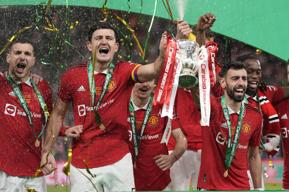 Manchester United's Bruno Fernandes, centre right, and Harry Maguire, second from left, hold the trophy during celebration as they won the English League Cup final soccer match between Manchester United and Newcastle United at Wembley Stadium in London, Sunday, Feb. 26, 2023. (AP Photo/Alastair Grant)