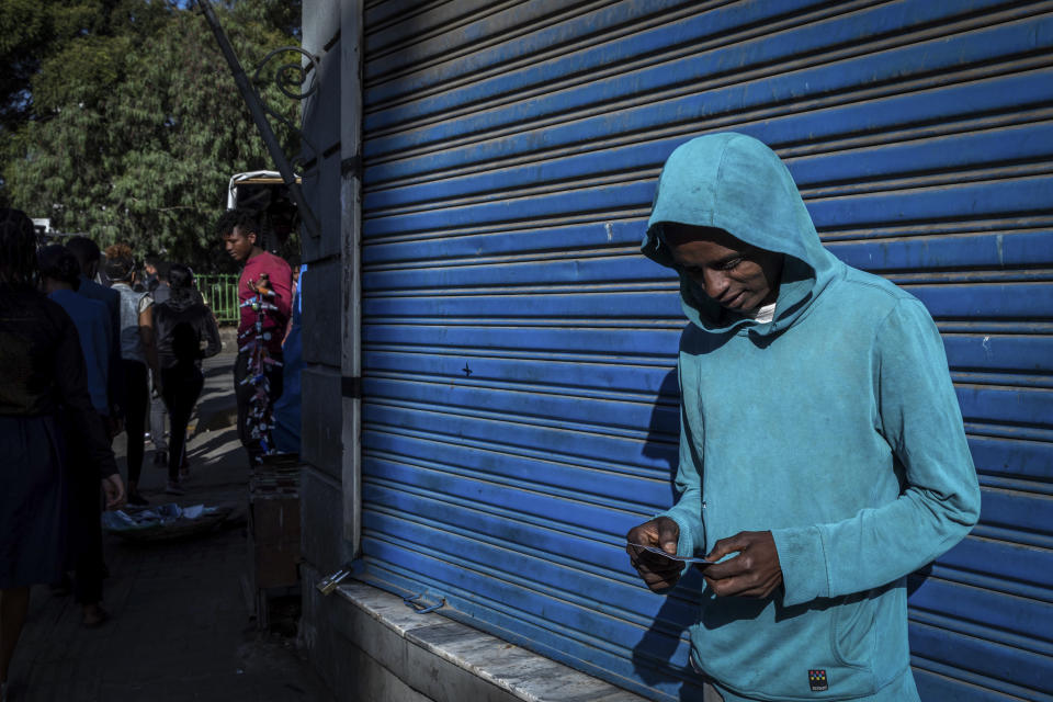 A man looks down as he holds his lottery ticket on a street in the capital Addis Ababa, Ethiopia Friday, Nov. 13, 2020. Tensions over the deadly conflict in Ethiopia are spreading well beyond its cut-off northern Tigray region, as the federal government said some 150 suspected "operatives" accused of seeking to "strike fear and terror" throughout the country had been detained. (AP Photo/Mulugeta Ayene)