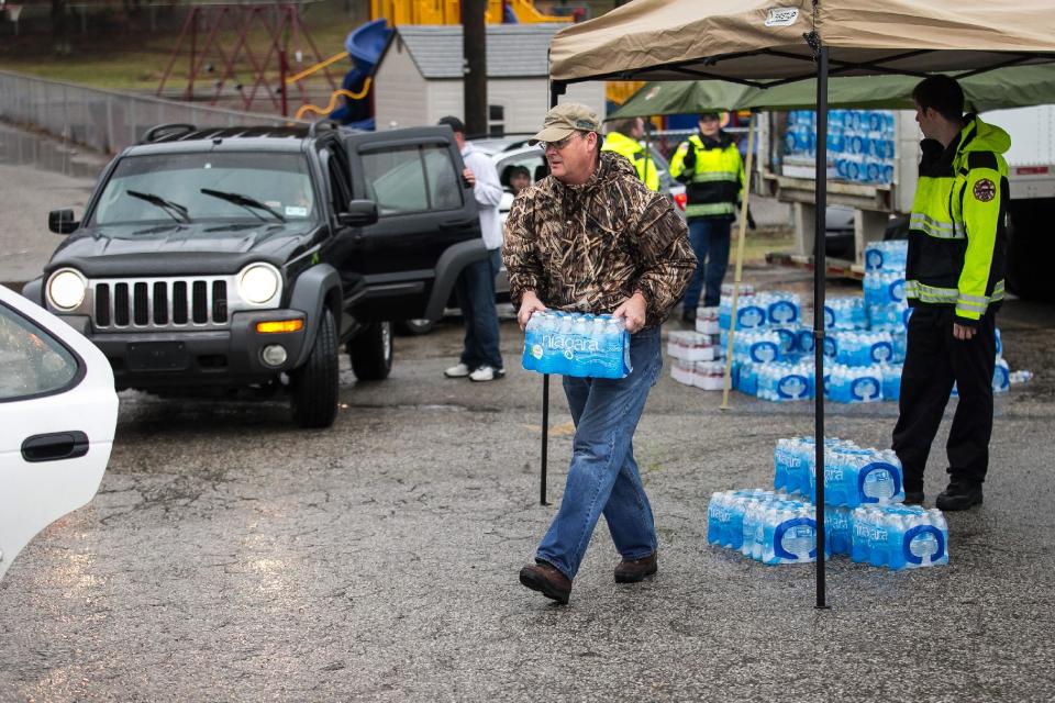 Members of Nitro Volunteer Fire Department help to distribute bottled water to local residents Saturday Jan. 11, 2014. The West Virginia National Guard was sent to distribute bottled water as residents bought up stock at local supermarkets following the chemical spill on Thursday, Jan. 9, 2014. (AP Photo Michael Switzer)