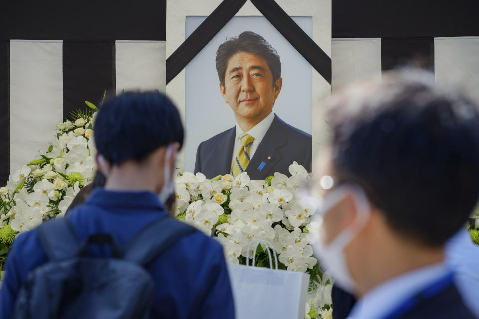 La gente deja flores y presenta sus respetos al ex primer ministro de Japón Shinzo Abe ante la sala Nippon Budokan en Tokio, el martes 27 de septiembre de 2022, antes de su funeral de estado. (Nicolas Datiche/Pool Photo via AP)