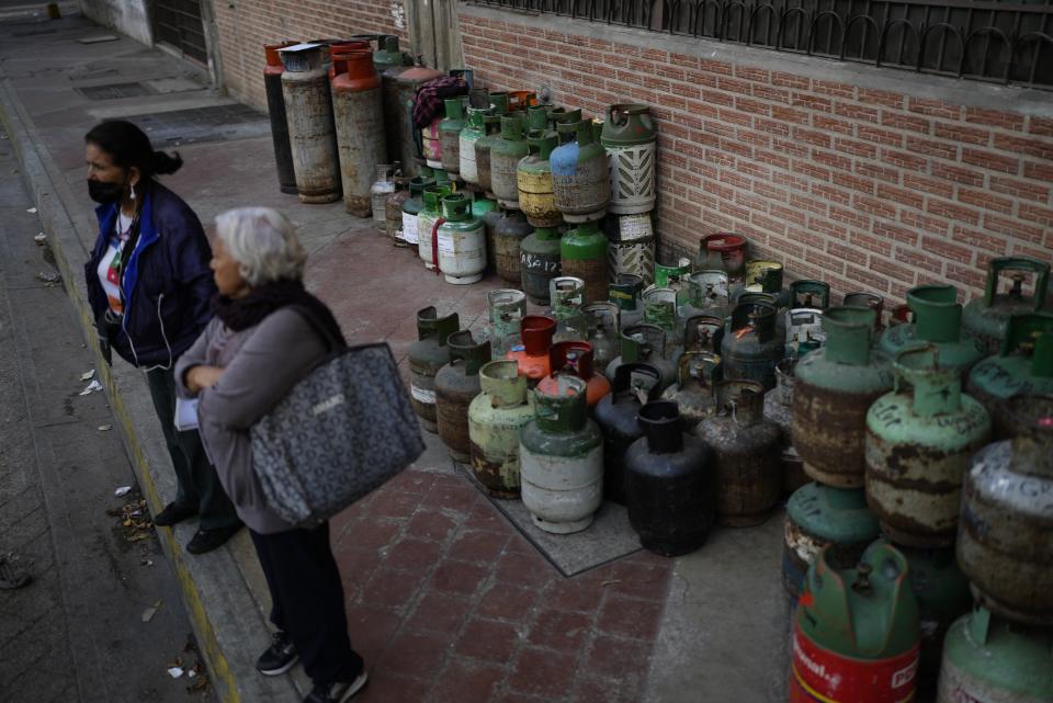 Women wait for a truck to pick up empty cooking gas tanks, that will in turn be refilled and returned in about two weeks, in Caracas, Venezuela, Thursday, March 2, 2023. The economic crisis has driven more than 7 million Venezuelans to leave their home country. (AP Photo/Ariana Cubillos)