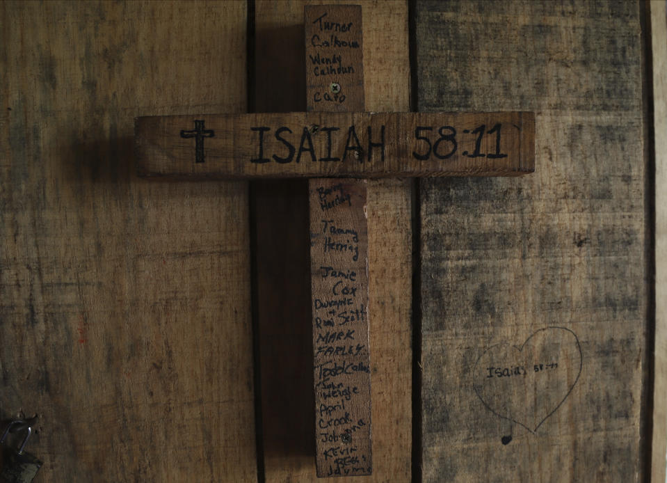 Una cruz de madera tiene grabado un verso bíblico y el nombre de miembros de la iglesia estadounidense que construyeron la casa en la que está colgada la cruz, en una zona antes controladas por las pandillas, en Santa Ana, El Salvador, el sábado 29 de abril de 2023. (AP Foto/Salvador Meléndez)