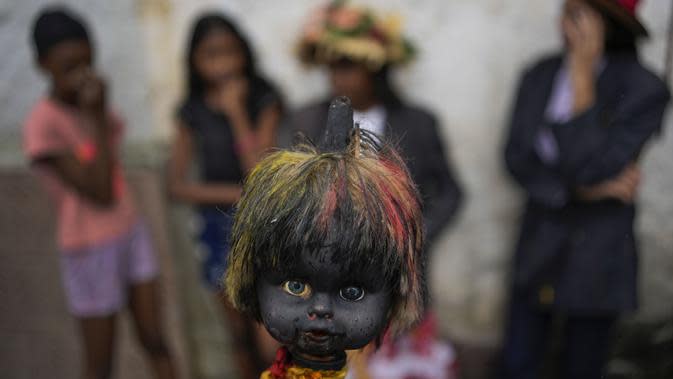 Orang yang bersuka ria berparade dengan kepala boneka yang ditusuk di atas tongkat selama perayaan Hari Tak Bersalah di Caucagua, Venezuela, Selasa (28/12/2021). Warga merayakan variasi hari raya itu dengan mengenakan pakaian tua, mengecat wajah mereka hitam dan lidah merah. (AP Photo/Matias Delacro
