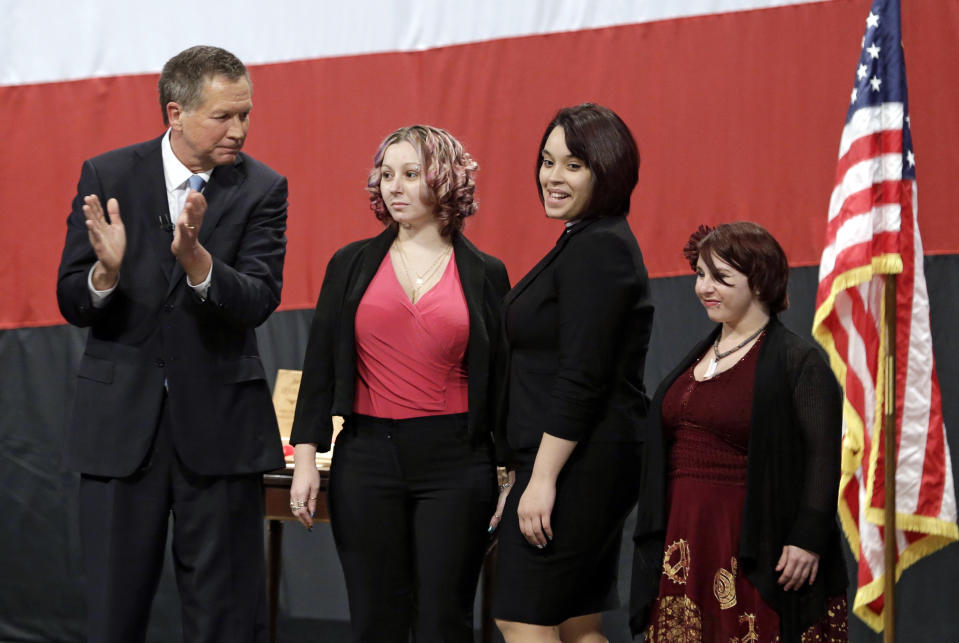 Ohio Gov. John Kasich, from left, introduces Amanda Berry, Gina DeJesus and Michelle Knight during his State of the State address at the Performing Arts Center Monday, Feb. 24, 2014, in Medina, Ohio. The three women, who survived a decades-long captivity in Cleveland before being rescued in May when Berry pushed her way through a door to freedom, received the Governor's Courage Award. (AP Photo/Tony Dejak)