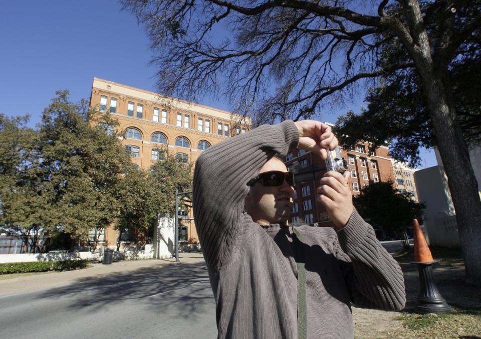 In this Wednesday, Jan. 5, 2011 photo, Rafael Boff of Brazil takes photographs while visiting Dealey Plaza, site of president John F. Kennedy's assassination, in Dallas. The building once used as a book depository is seen in the background. (AP Photo/Tony Gutierrez)