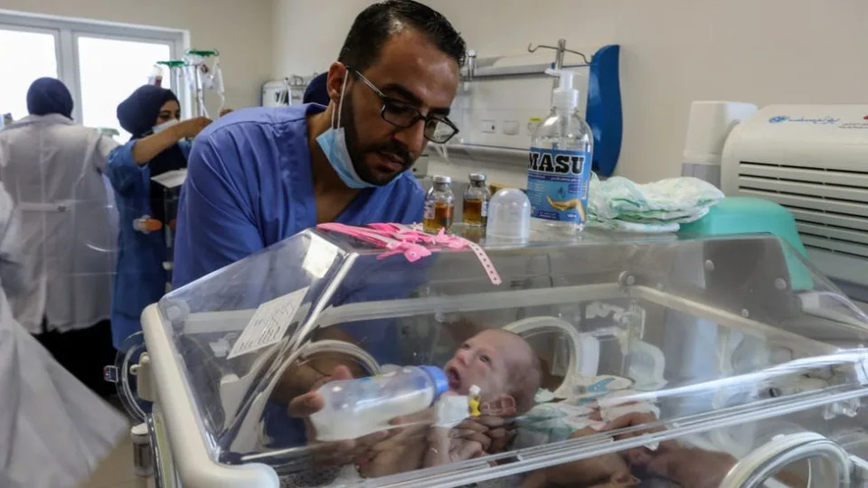 A member of hospital staff moves a baby in an incubator out of Al-Shifa hospital in Gaza City