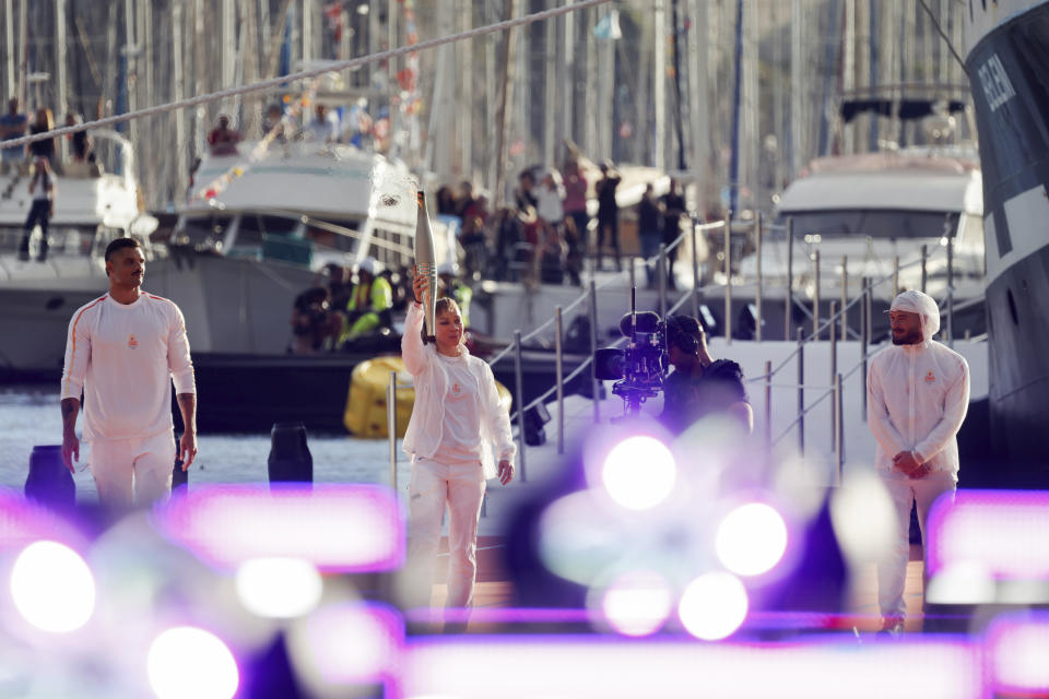 French Paralympic athlete Nantenin Keïta, center, holds the Olympic torch next to French swimmer Florent Manaudou, left, and French rapper Jul in Marseille, southern France, Wednesday May 8, 2024. After leaving Marseille, a vast relay route is undertaken before the torch odyssey ends on July 27 in Paris. The Paris 2024 Olympic Games will run from July 26 to Aug.11, 2024. ( (Ludovic Marin, Pool via AP)