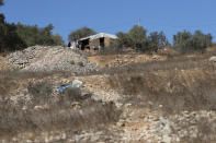 A Jewish settler watches from the settlers outpost that overlooks Palestinian olive groves, in the West Bank village of Burqa, East of Ramallah, Friday, Oct. 16, 2020. Palestinians clashed with Israeli border police in the West Bank on Friday during their attempt to reach and harvest their olive groves near a Jewish settlers outpost. (AP Photo/Nasser Nasser)