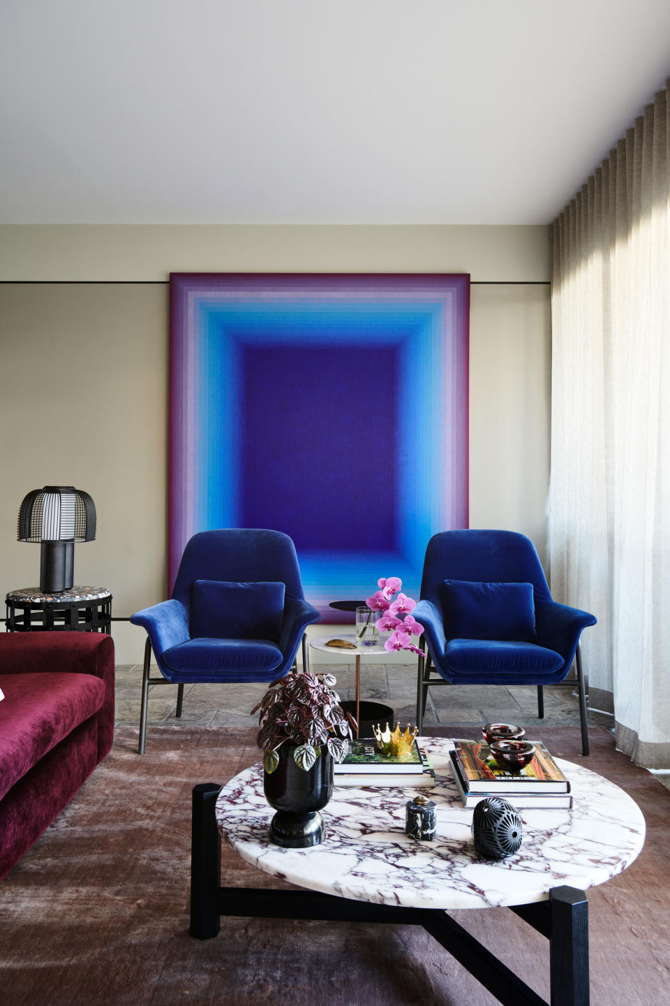 a living room with blue chairs and ombre wall art