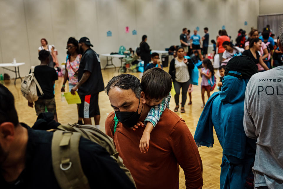 Rahmat Gul Safi, an Afghan refugee and a former Afghan soldier who worked alongside American troops, carries his son Rahimudin, 3, on his back after the family went to collect free back-to-school supplies organized by the Des Moines Refugee Support. / Credit: Marcus Yam