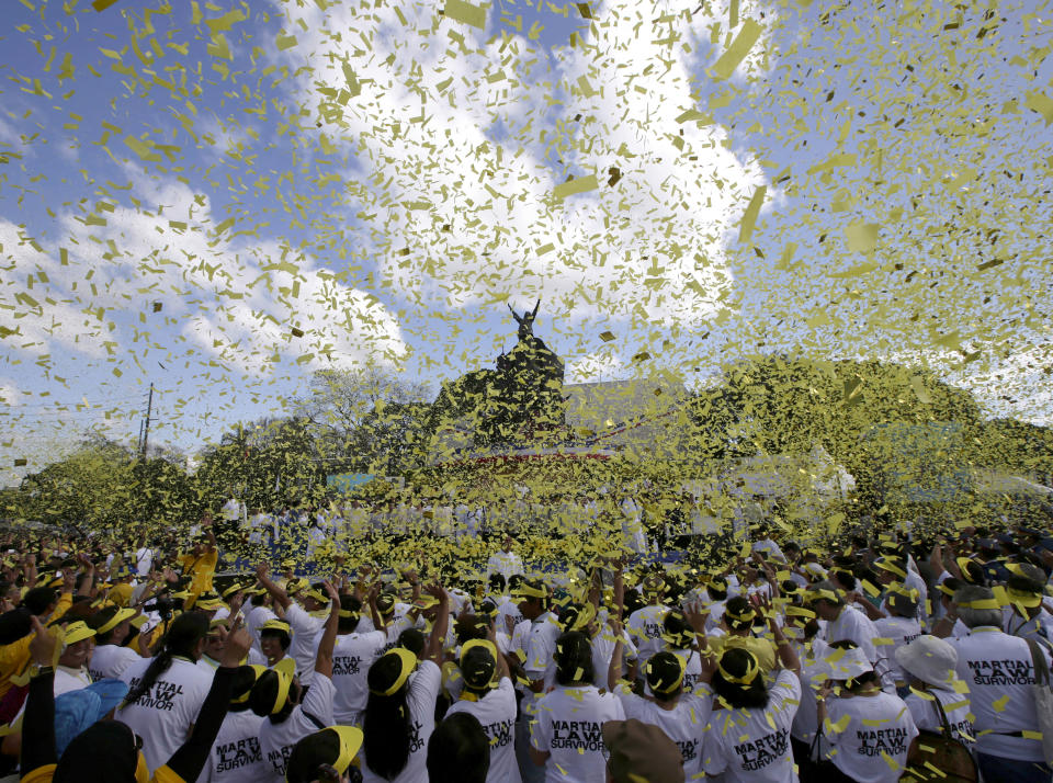 FILE - In this Feb. 25, 2013, file photo, yellow confetti rains on hundreds of people visiting the People Power Monument along EDSA Boulevard, in Quezon city northeast of Manila, Philippines, to celebrate the 27th anniversary of the People Power Revolution. The army-backed uprising that ousted authoritarian leader Ferdinand Marcos was also dubbed the "Yellow Revolution" for the color that united massive numbers of protesters from all walks of life. (AP Photo/Bullit Marquez, File)