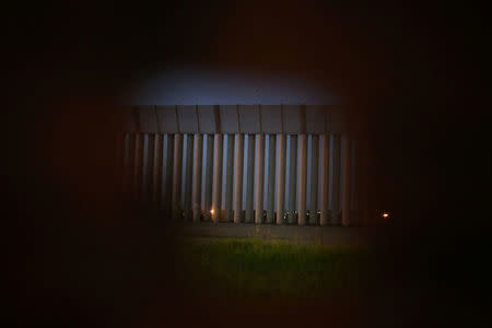 The border fence separating Mexico and the United States is seen through a hole of a second border fence in an area where double border fences were built, in Tijuana, Mexico. REUTERS/Edgard Garrido