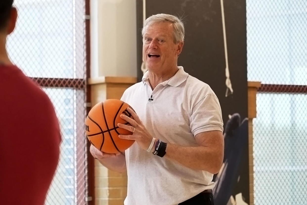 Charlie Baker holds a basketball while giving an interview on indoor court (NBC News)